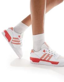 Oferta de Adidas Originals Rivalry trainers in white and pink with heart details por $52 en ASOS