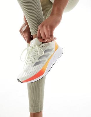 Oferta de Adidas Running Duramo SL trainers in off white and orange por $65 en ASOS