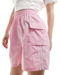 Oferta de Adidas Originals three stripe cargos shorts in pink por $34 en ASOS