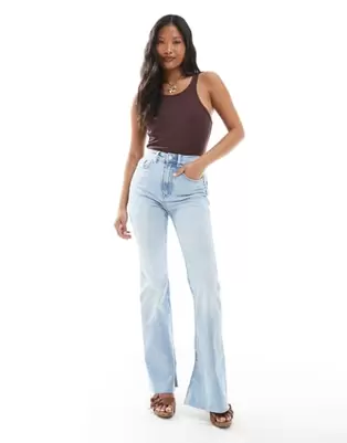 Oferta de Stradivarius Petite D74 flare slit jean in light wash por $29.99 en ASOS