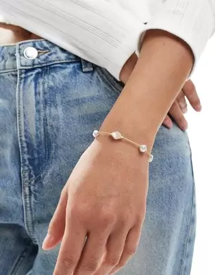 Oferta de ASOS DESIGN bracelet with faux pearl and fine chain design in gold tone por $6 en ASOS
