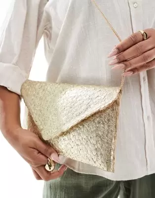Oferta de Glamorous metallic straw envelope clutch bag in gold por $26 en ASOS